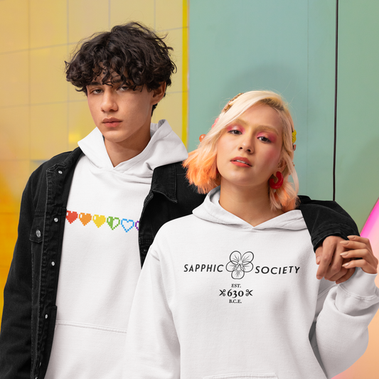 two young people pose in white hoodies featuring queer geekery's colourful pixelated pride hearts design and its sapphic society design